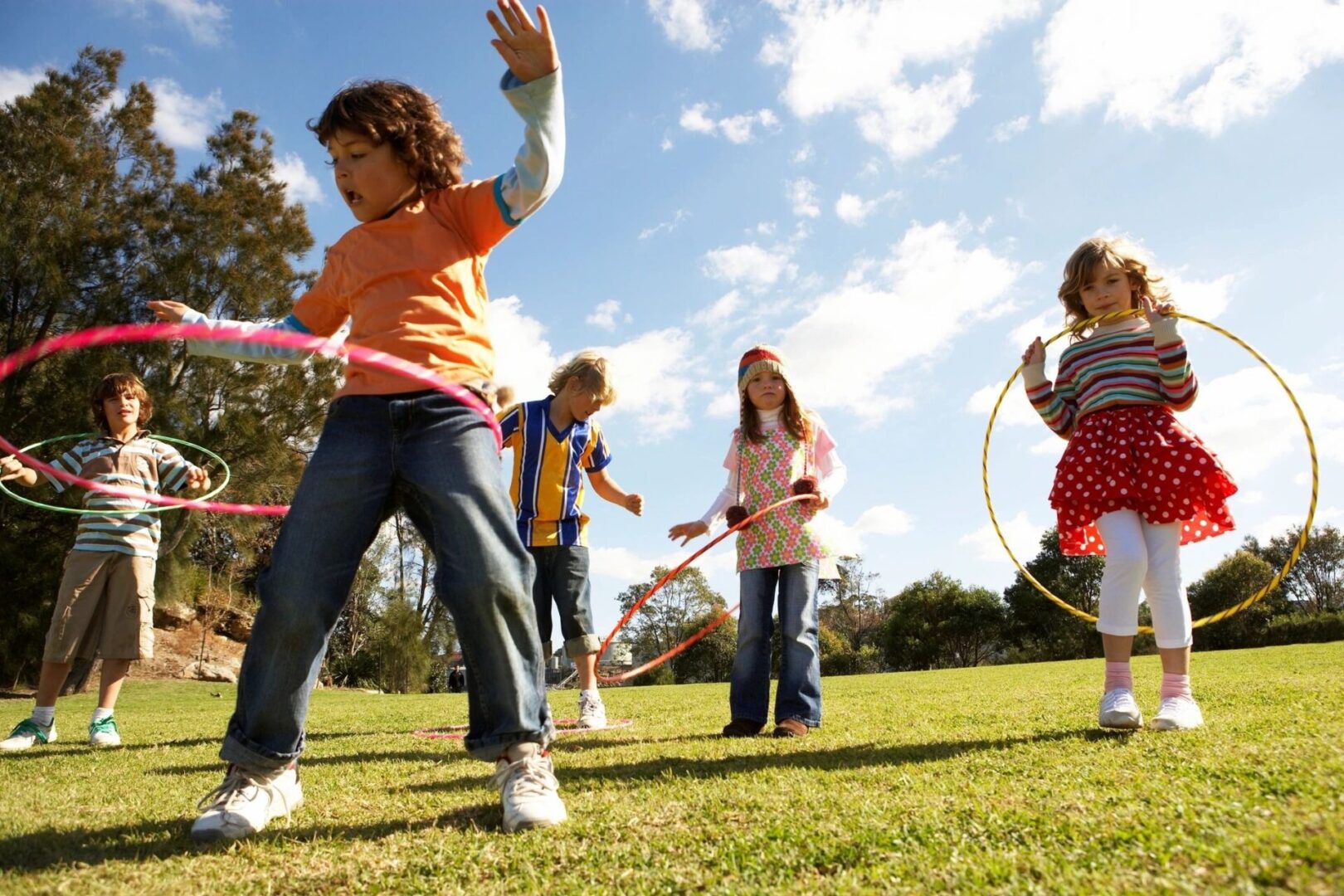 A group of children playing with hula hoops in the park.