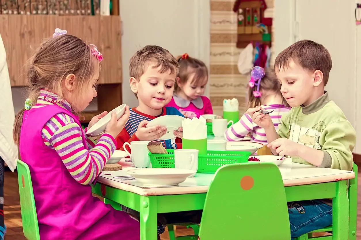 A group of children sitting at a table eating food.