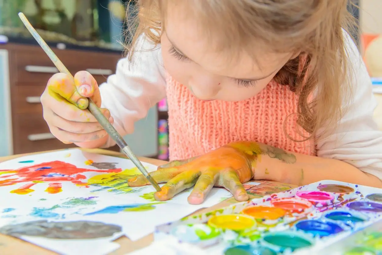 A little girl is painting with her hands.