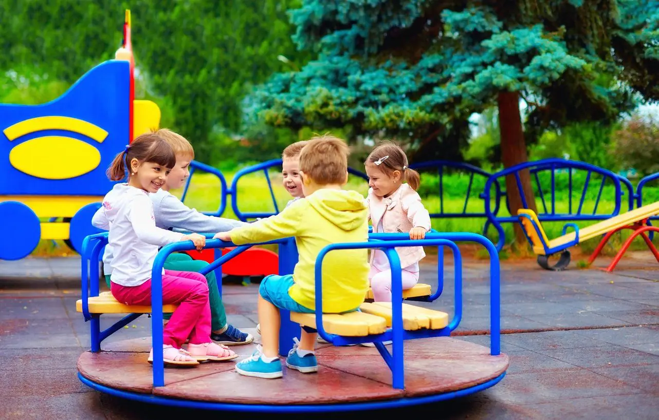 A group of children sitting on top of a merry go round.